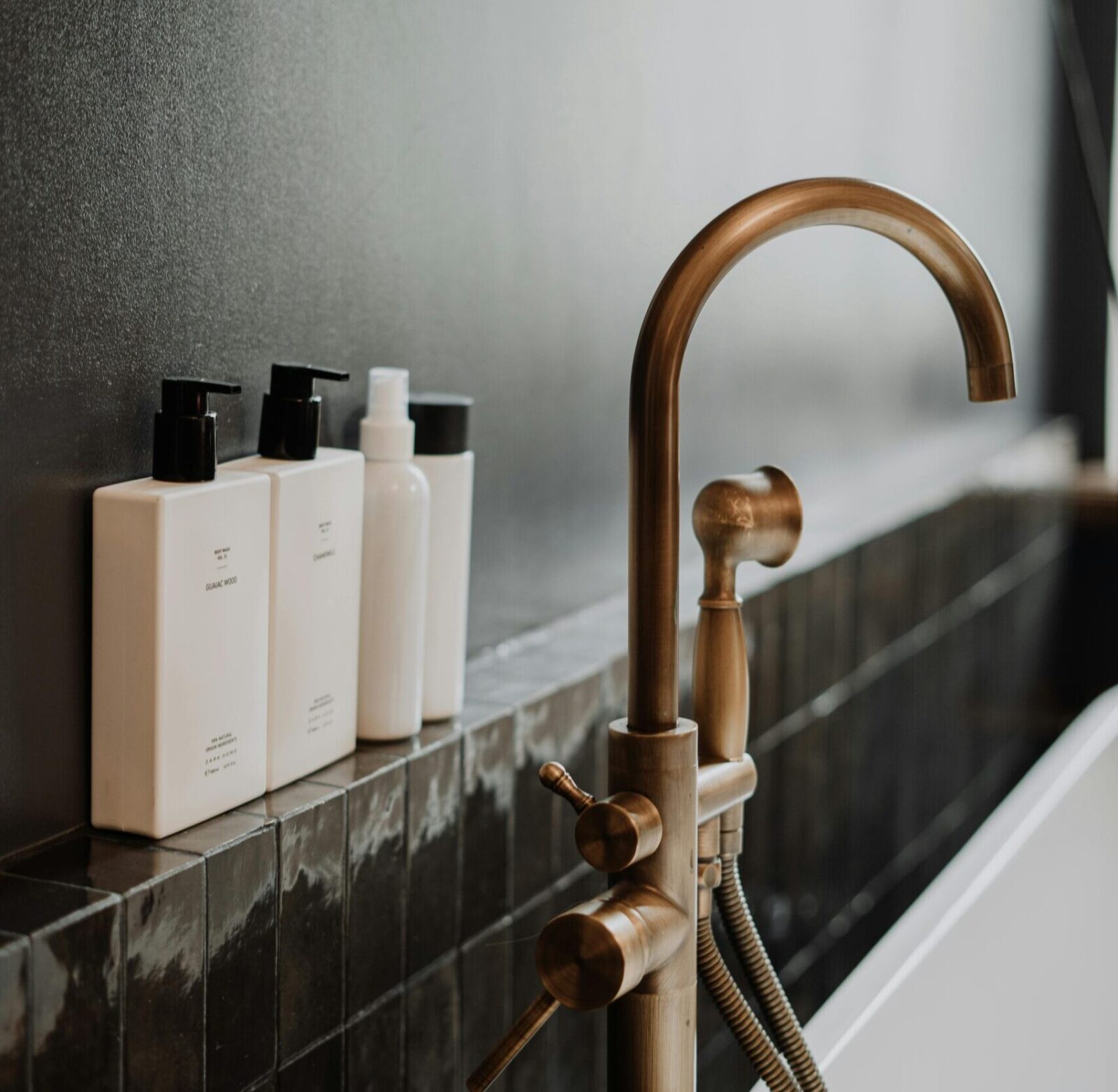Sleek modern bathroom featuring a golden water tap and minimalist bottles.